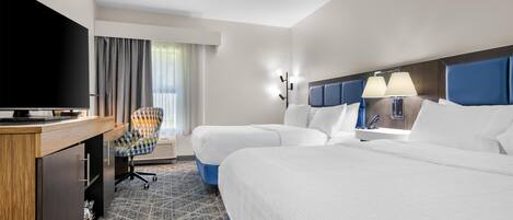 A hotel room with a bed, a desk, a chair, and a television.