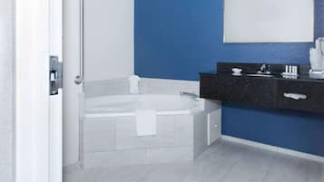 Een badkamer met een witte badkuip, een zwart aanrecht en een blauwe wand.