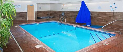 A swimming pool with clear blue water, tiled edges, and a blue lifeguard chair.