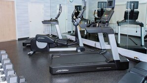 Une salle de sport équipée de tapis de course, d’haltères et d’un appareil elliptique de la marque Life Fitness.