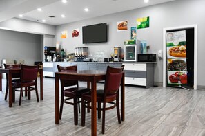 A modern breakfast area with a counter, coffee machines, and seating. - Quality Inn & Suites Brooks Louisville South (Brooks)