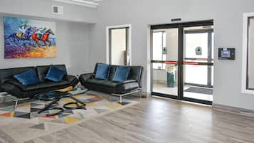 A lobby with two black leather sofas, a colorful abstract painting, and a patterned rug.