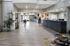Welcome to our hotel, featuring a reception desk, seating area, and potted plant amidst a herringbone tile floor.