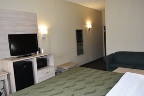A hotel room with a bed, a television, a microwave, a small refrigerator, a nightstand, a lamp, and a couch. -  Quality Inn & Suites Brooks Louisville South (Brooks)
