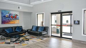 Eine moderne Lobby mit zwei schwarzen Ledersofas, einem farbenfrohen abstrakten Gemälde und einem Teppich mit geometrischem Muster.