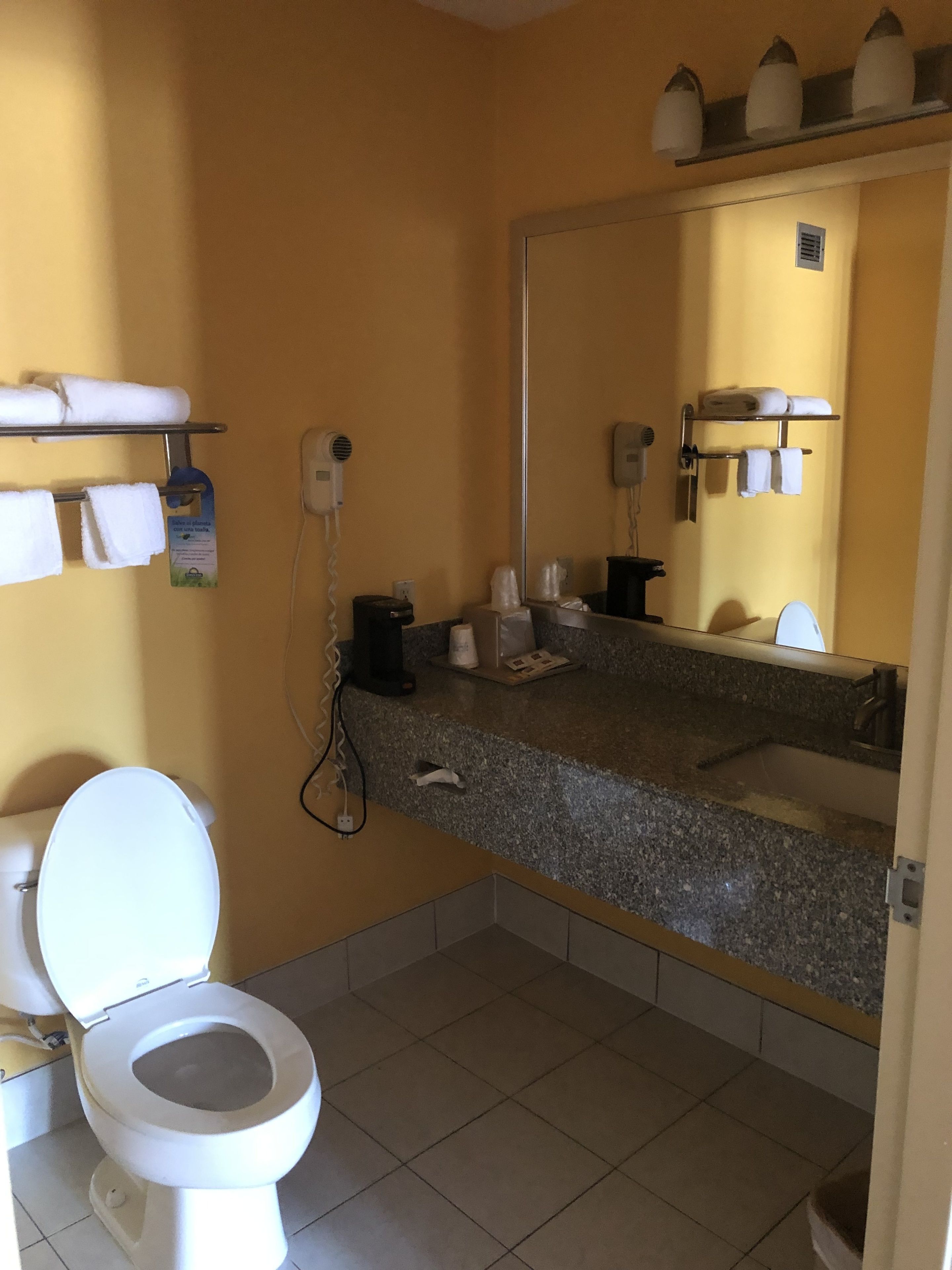 Ein Badezimmer mit Toilette, Waschbecken, Spiegel und Handtuchhaltern.