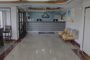 Zona de recepción con mostrador, área de asientos con sillones e indicaciones en el suelo.
