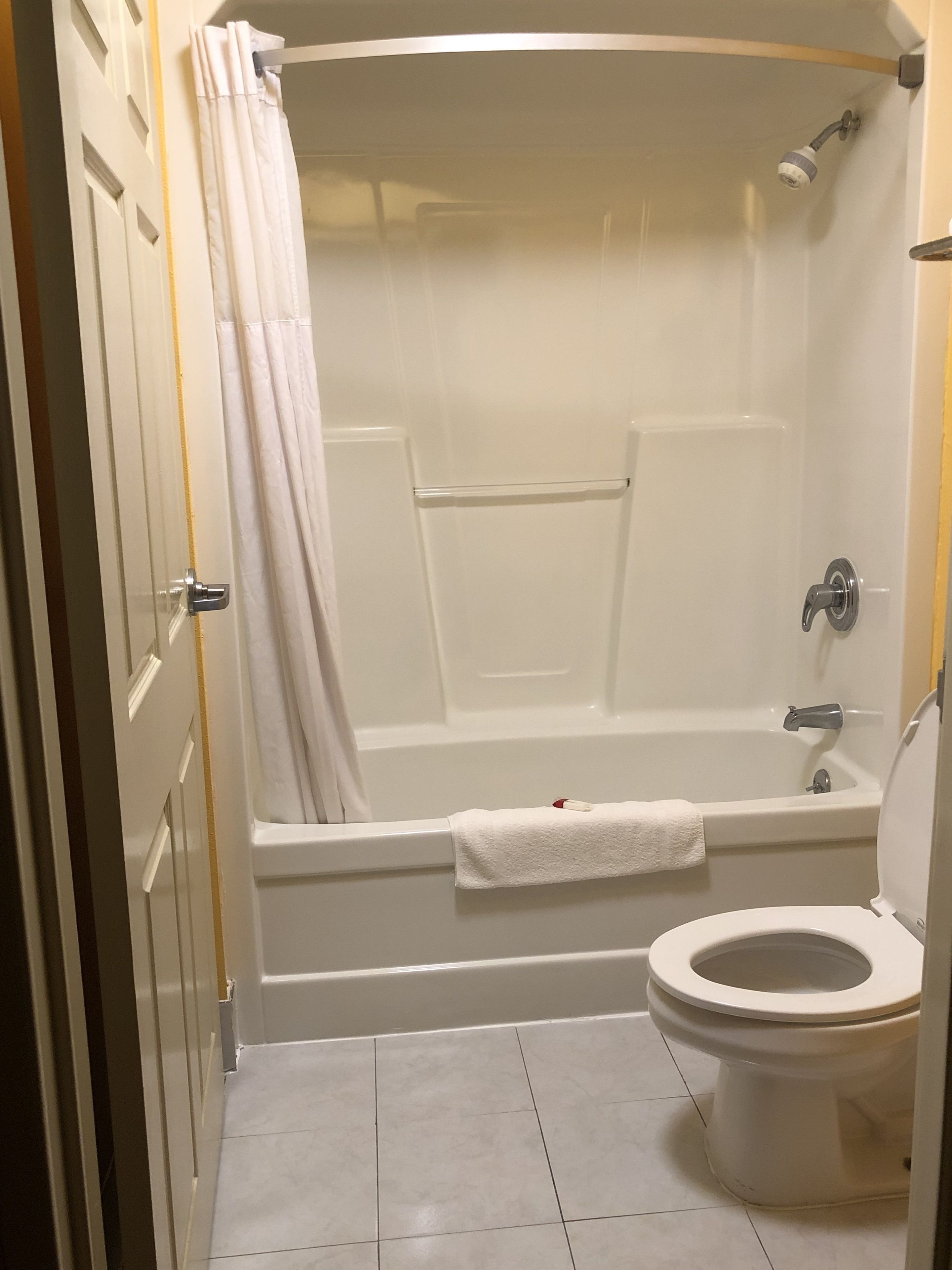 A bathroom with a bathtub, toilet, and a shower curtain.