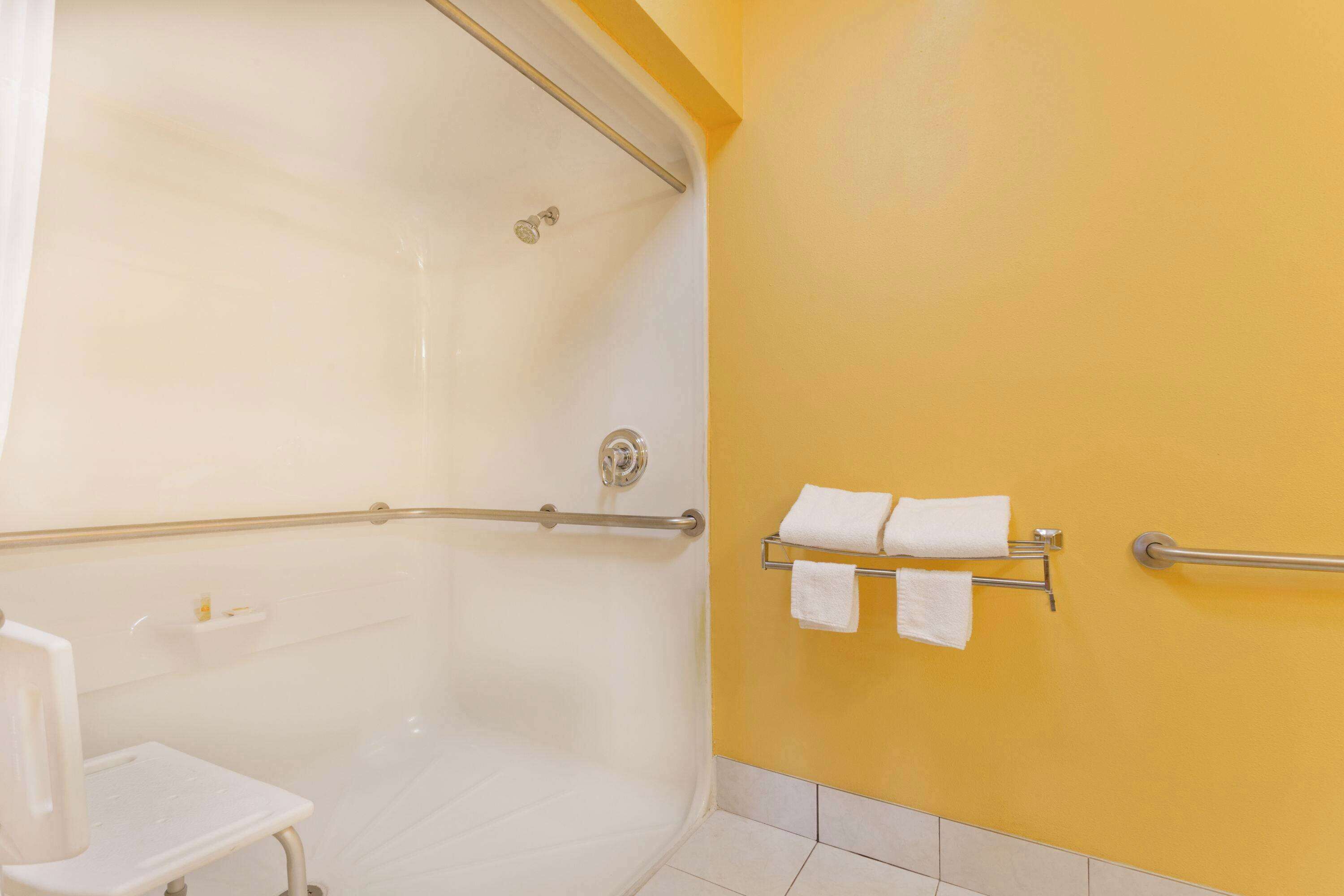 Un baño con ducha, un lavabo blanco y un perchero con dos toallas.