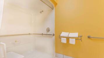 Un baño con ducha, un lavabo blanco y un perchero con dos toallas.