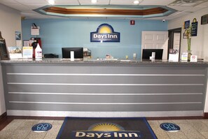 A reception desk with a Days Inn logo, a computer, and a plant. - Days Inn by Wyndham Franklin (Franklin)