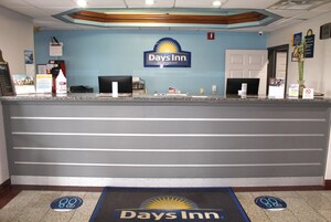 Una recepción con el logotipo de Days Inn, una computadora y una planta.
