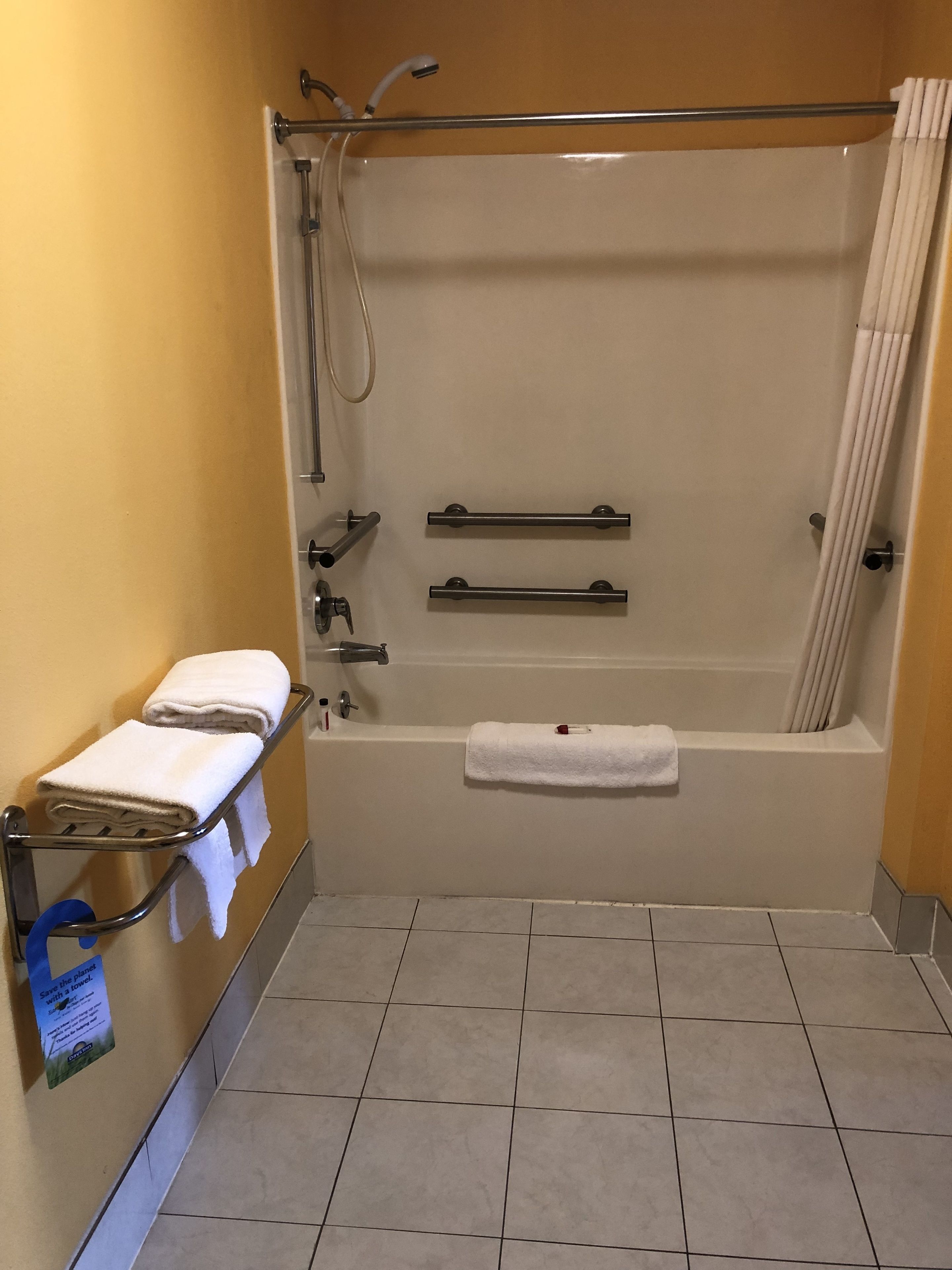 A standard bathroom with a bathtub, a shower, and a towel rack.