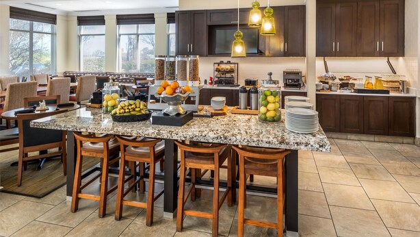 A spacious kitchen with granite countertops, wooden bar stools, and a large island. - Hilton Garden Inn Lexington Hamburg (Lexington)