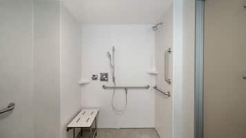 A small, enclosed shower area with a bench, grab bars, and a handheld showerhead.
