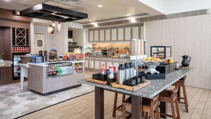 Una cocina moderna con encimeras de granito, una isla central con utensilios de bar, un enfriador de vino y una variedad de electrodomésticos.