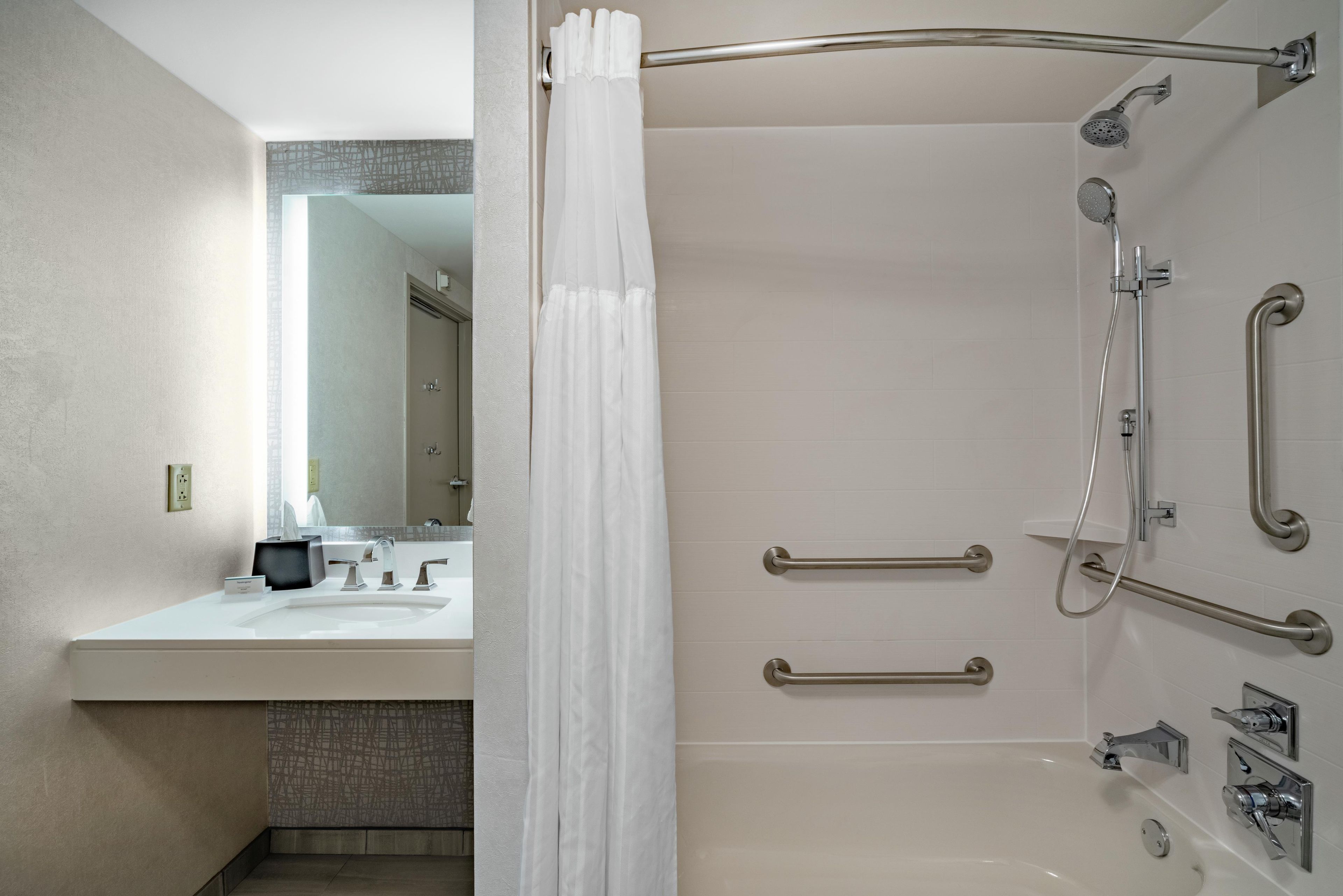 A modern bathroom with a shower, a vanity with a mirror, and a toilet.