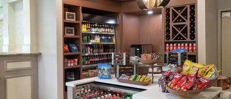 A well-stocked beverage refrigerator with various sodas and juices, a snack display with chips and cookies, and a section with bottled water and other drinks.