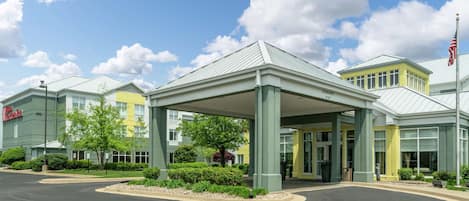 A hotel with a covered entrance, multiple buildings, and a flag.