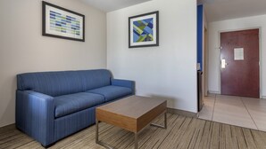 A room with a blue sofa, a wooden coffee table, and two framed artworks on the walls.