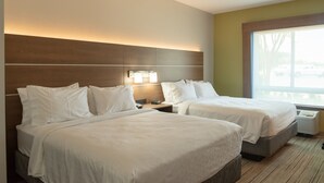 A hotel room with two beds, a nightstand, a lamp, and a large window.