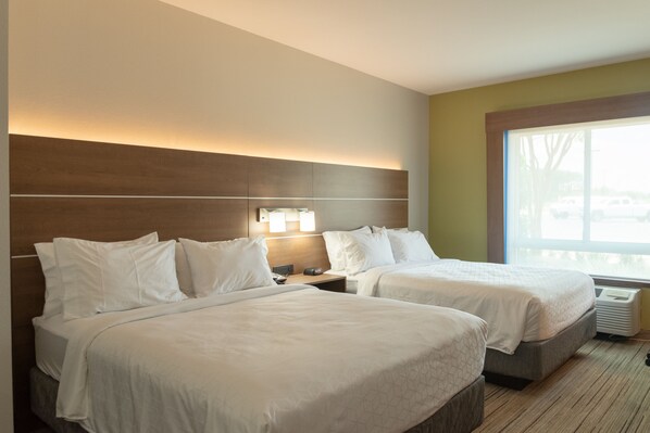 Une chambre d’hôtel avec deux lits, une table de chevet, une lampe et une grande fenêtre.