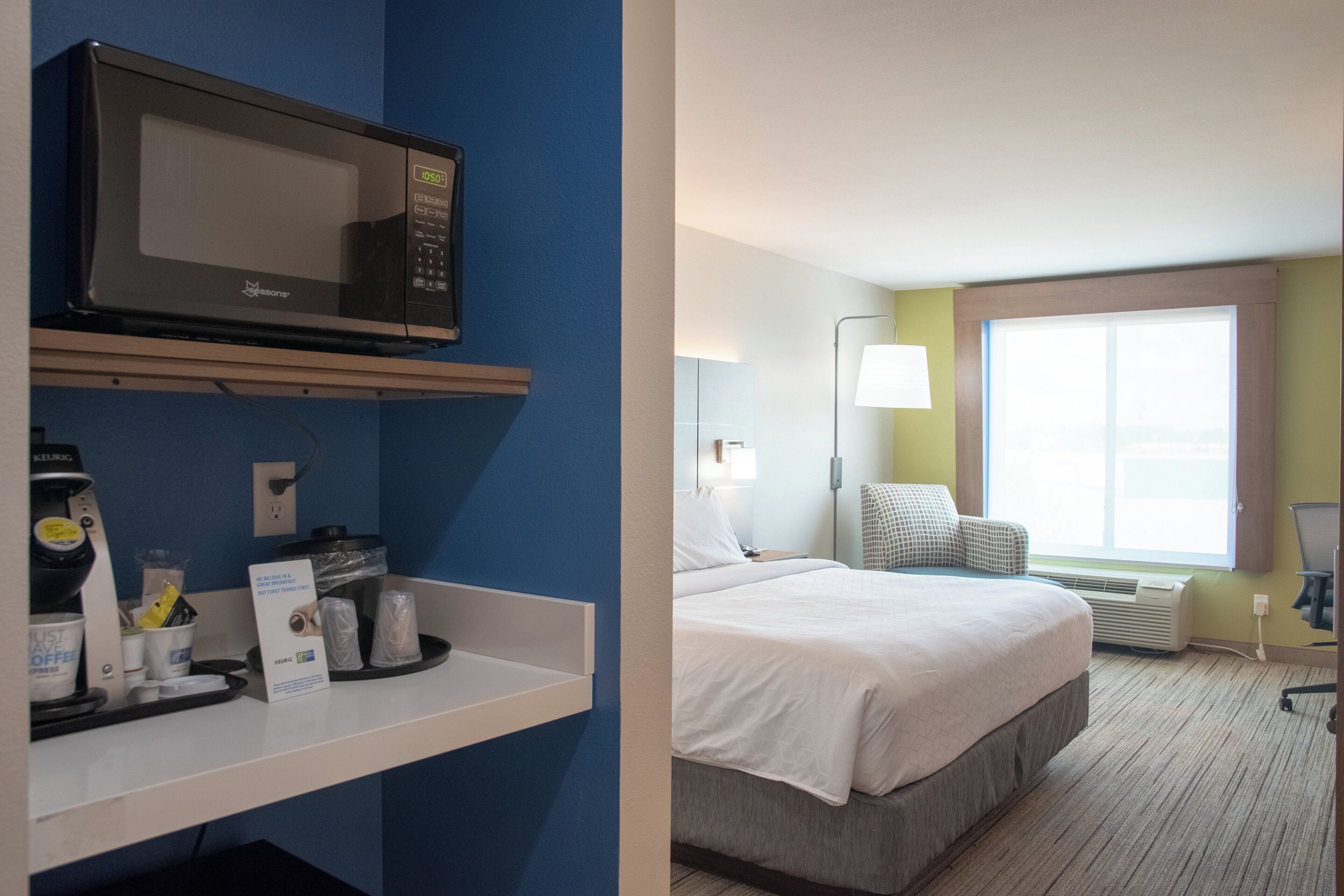 A hotel room with a bed, a microwave, a coffee machine, and a window with a view.