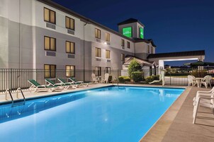 Una piscina al aire libre, sillones reclinables de piscina