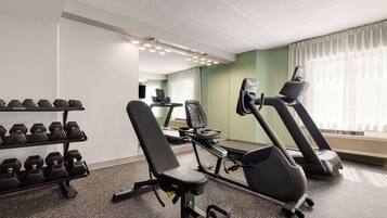Ein Fitnessraum mit Laufbändern, einer Bank und Kurzhanteln.