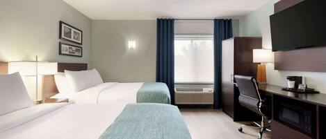 A hotel room with two beds, a desk, a television, and a window with curtains.