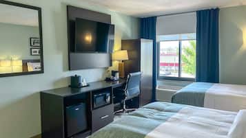 A hotel room with a bed, a desk, a TV, and a window with curtains.