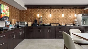 A modern kitchen with dark wood cabinets, a microwave, a coffee machine, and a breakfast bar with a glass display case. - Wingate by Wyndham Salisbury MD Airport North (Salisbury)