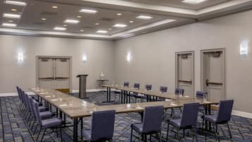 A conference room with a long table, multiple chairs, and a podium.