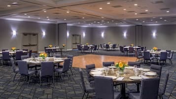 A conference room with round tables, chairs, and floral centerpieces.