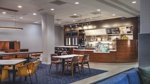 A modern restaurant with a bar area, seating arrangements, and a counter with a menu display.