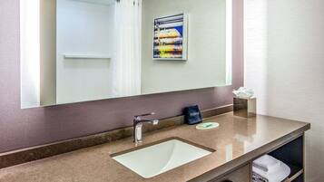 A bathroom with a large mirror, a sink, a towel rack, and a makeup station.