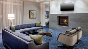 A modern living room with a sectional sofa, a glass coffee table, and a fireplace.