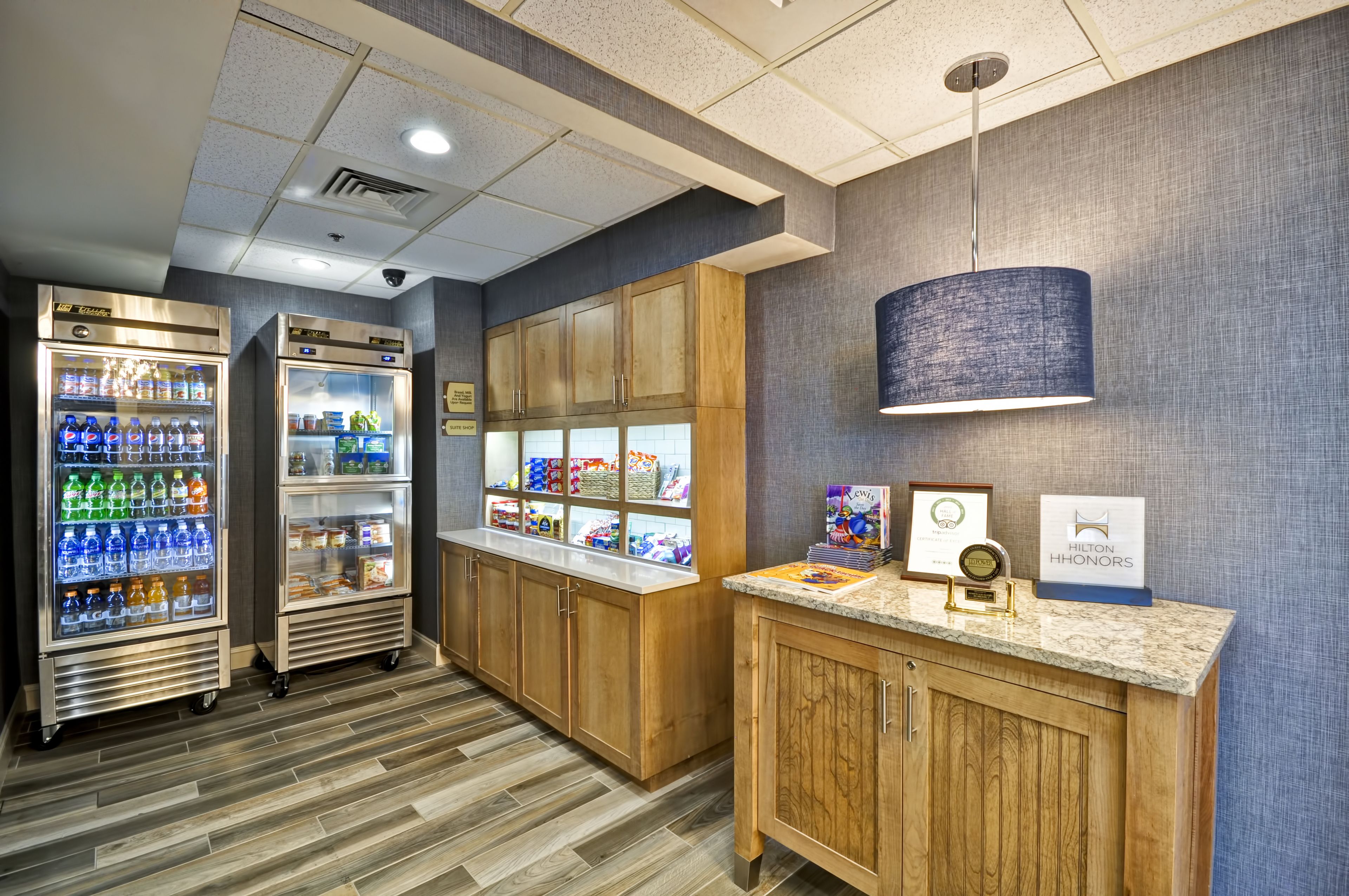 A hotel reception area with wooden cabinets, a marble counter, and two beverage dispensers.