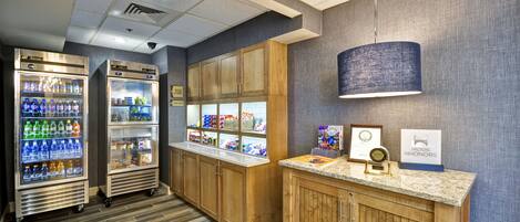 A hotel reception area with wooden cabinets, a marble counter, and two beverage dispensers.