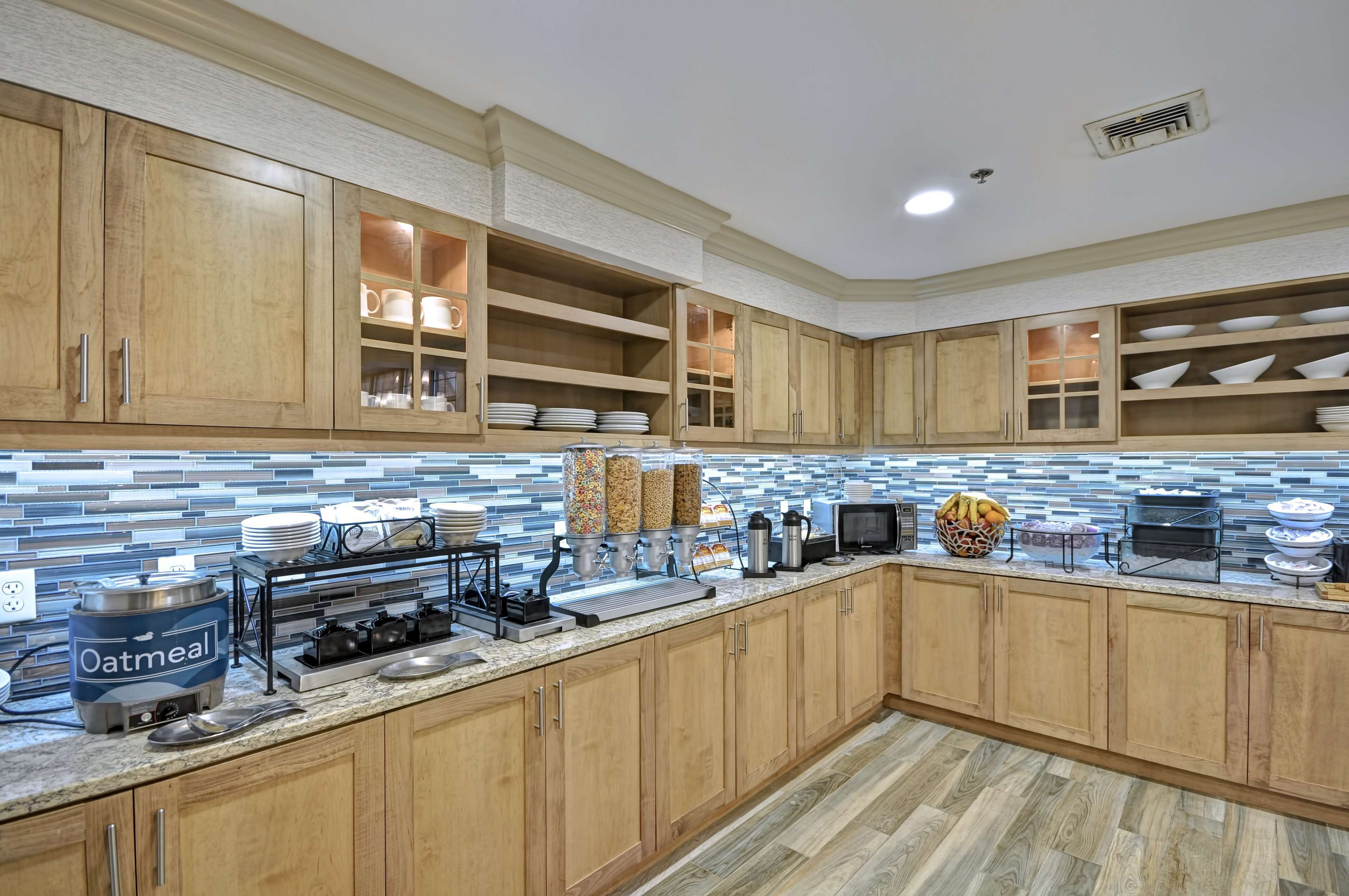 A modern kitchen with wooden cabinets, a tiled backsplash, and various appliances.