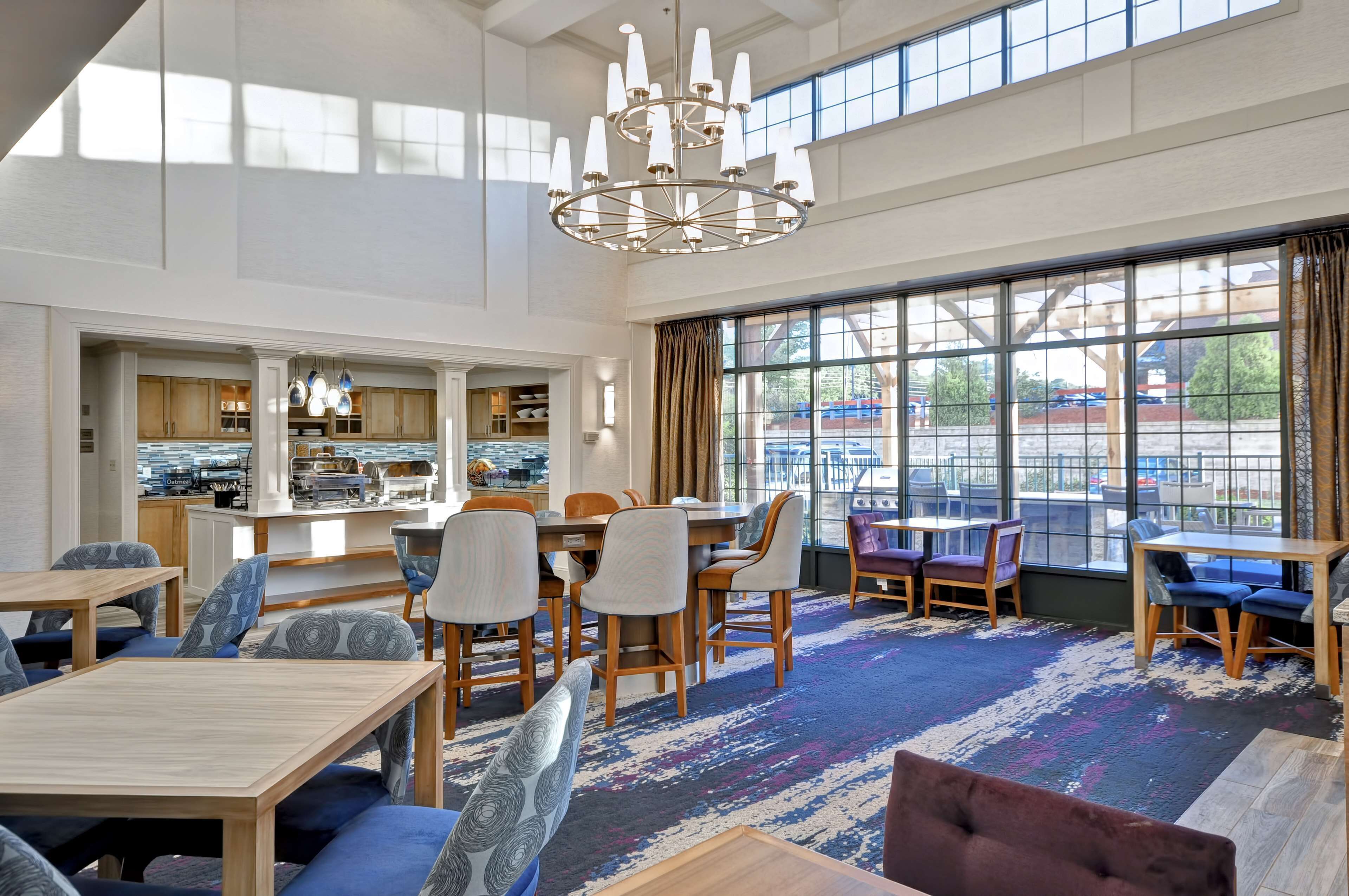 A spacious dining area with high ceilings, large windows, and a chandelier.