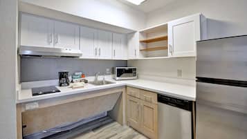Una cocina moderna con gabinetes blancos, un refrigerador de acero inoxidable, un microondas y un lavavajillas.