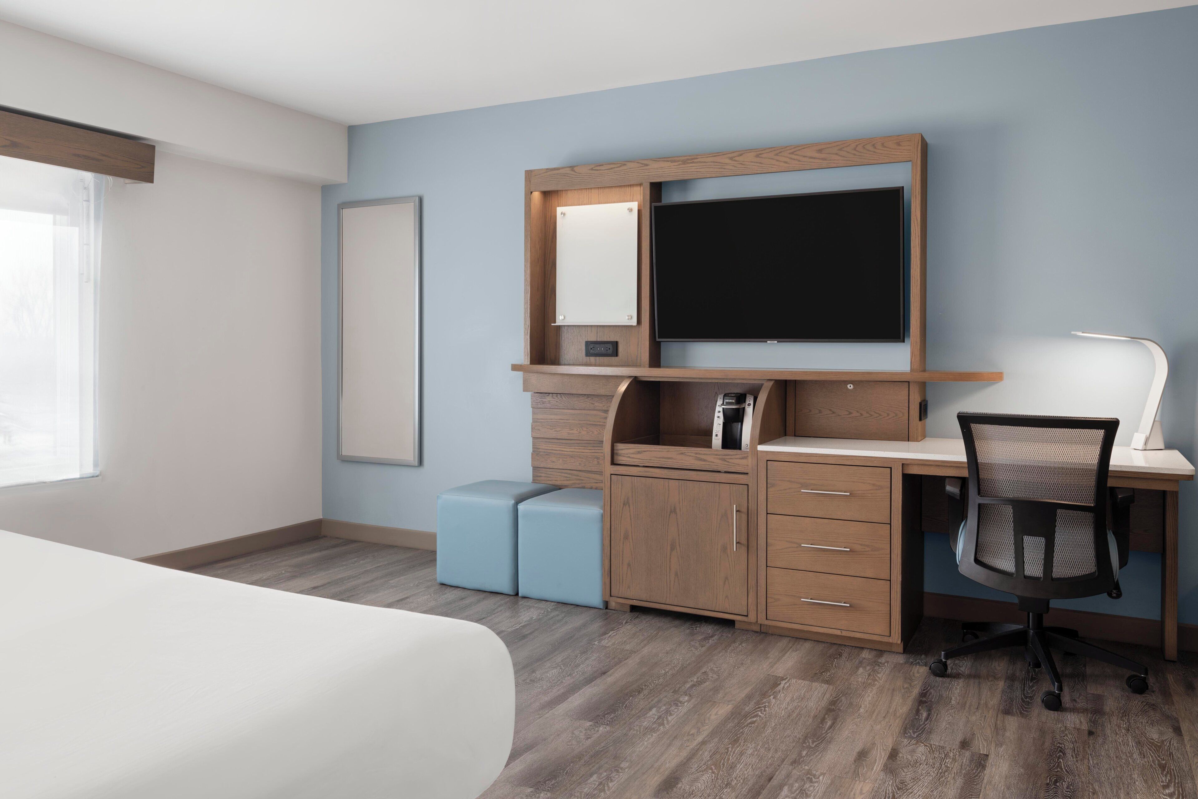 A bedroom with a bed, a desk with a computer, a chair, and a wardrobe.
