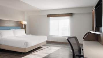 A hotel room with a bed, desk, chair, and a window.