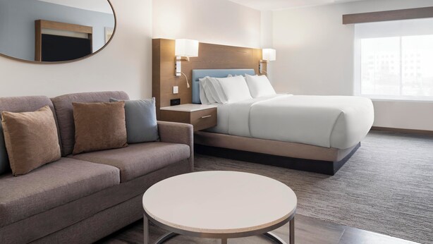 Ein Hotelzimmer mit Bett, einer Sitzecke, einem runden Tisch und einem an der Wand befestigten Fernseher.