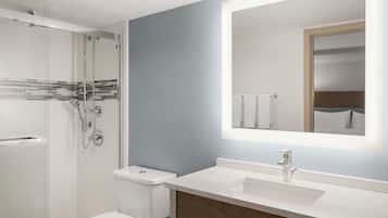 A modern bathroom with a glass shower enclosure, a white toilet, and a vanity with a mirror.