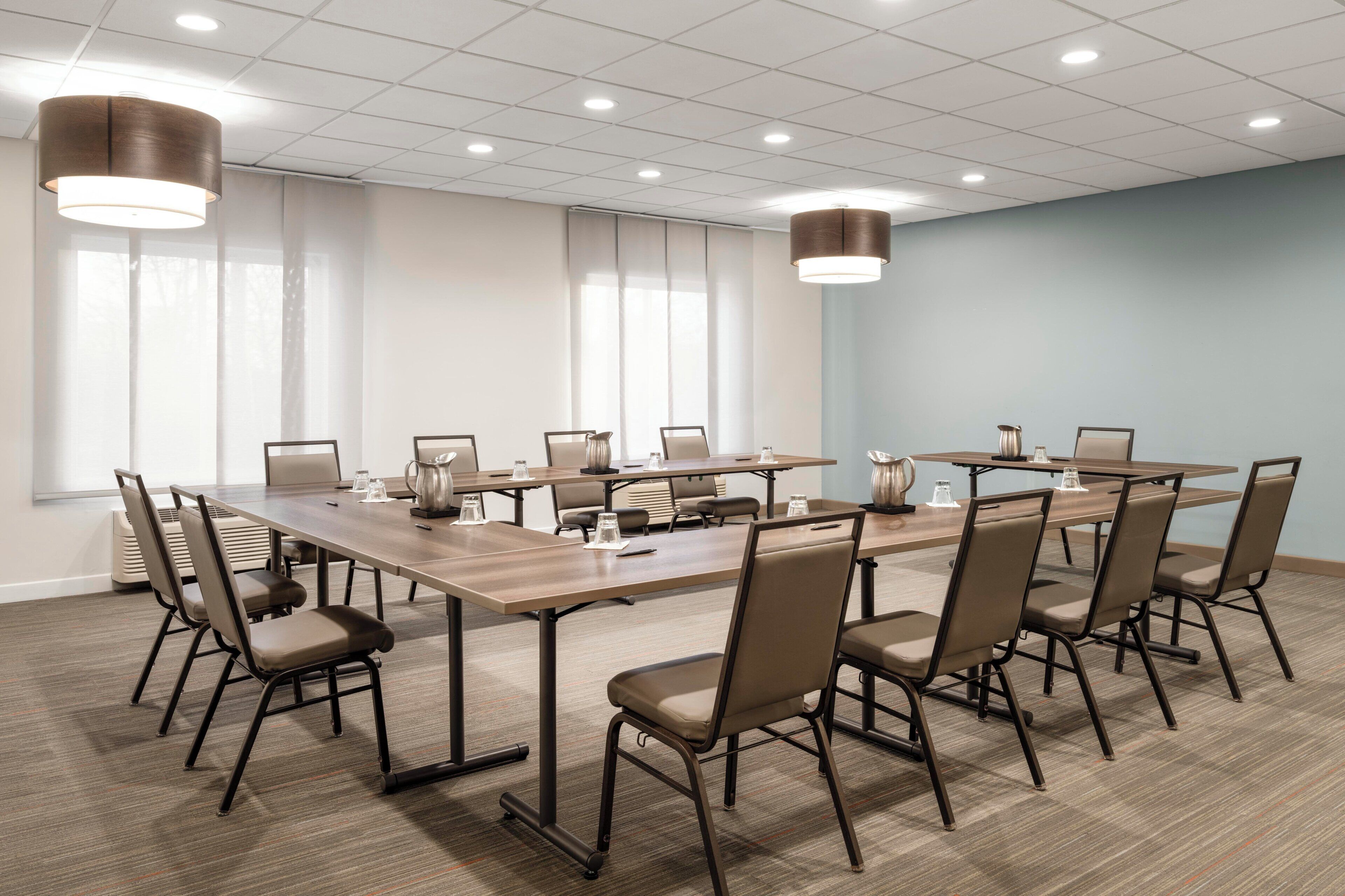 Un salón de conferencias con una mesa larga, sillas e iluminación colgante.
