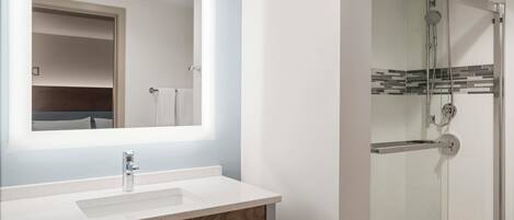 Un baño con un espejo grande, un lavabo y una ducha con paredes de vidrio.
