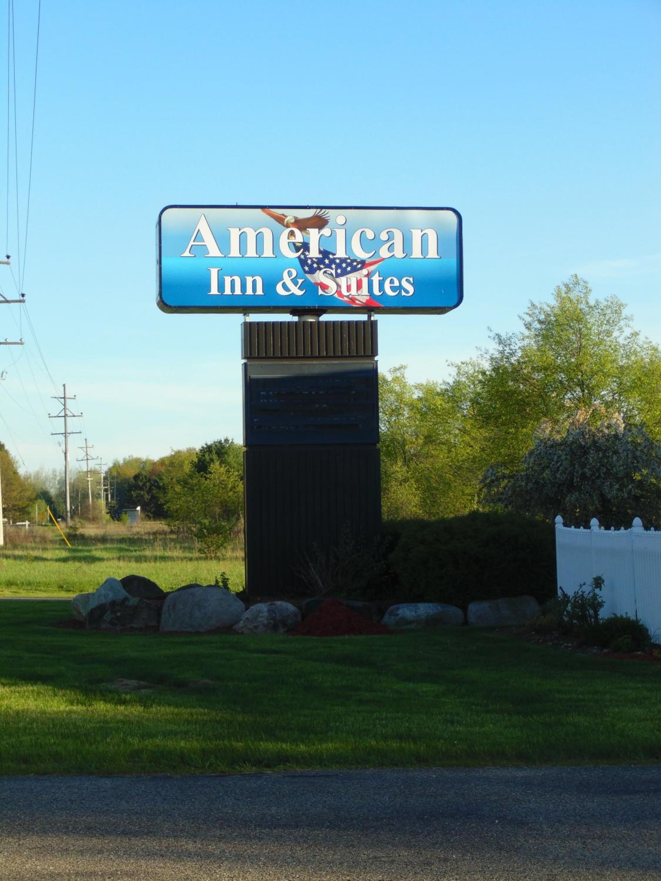 Un letrero de American Inn & Suites con una vista despejada del paisaje circundante.