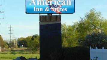 Un letrero de American Inn & Suites con una vista despejada del paisaje circundante.